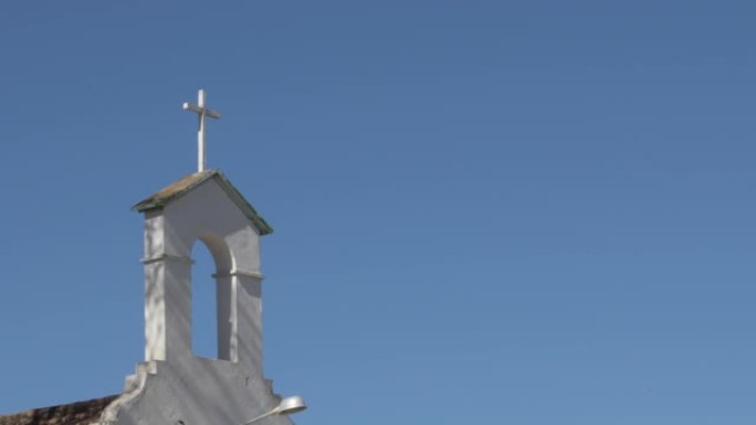 阳光明媚的日子，在安达卢西亚乡村教堂的白色钟楼中的旧十字架