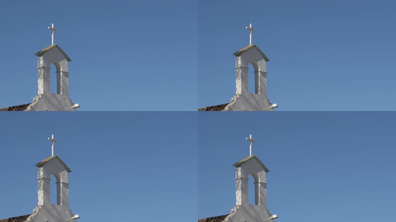 阳光明媚的日子，在安达卢西亚乡村教堂的白色钟楼中的旧十字架
