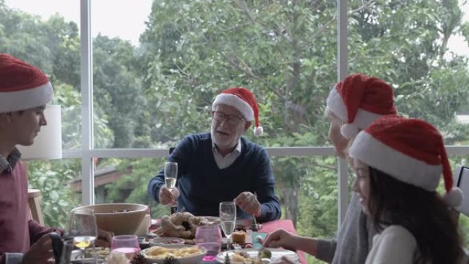 干杯，老人戴红帽子，在圣诞节与家人共进晚餐，他们很开心，一起庆祝欢呼，