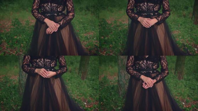 穿着黑色郁郁葱葱的复古连衣裙的哥特式女王在大自然中摆姿势。女人担心