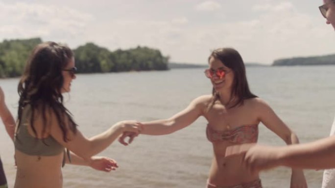 朋友在湖边的海滩上跳舞和聚会，一名年轻女子开始用牙线剔牙