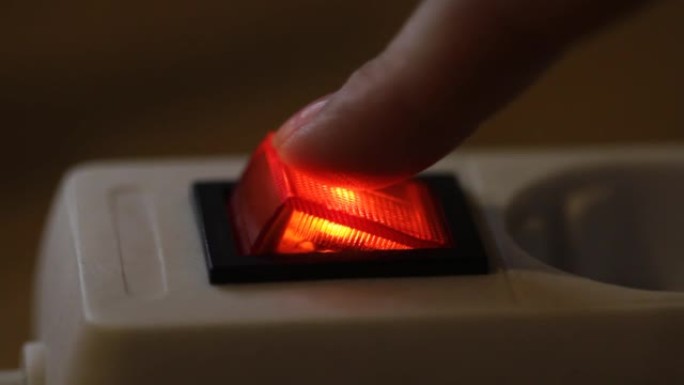 女性手指按下红色开/关电源按钮。特写视频，选择性聚焦