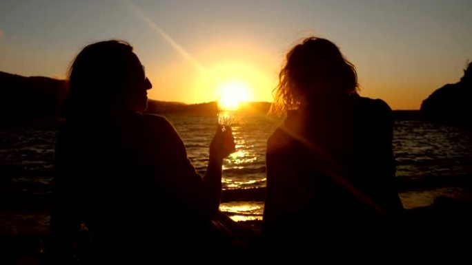 妇女坐在海边，日落时喝饮料。希腊。慢动作。高清