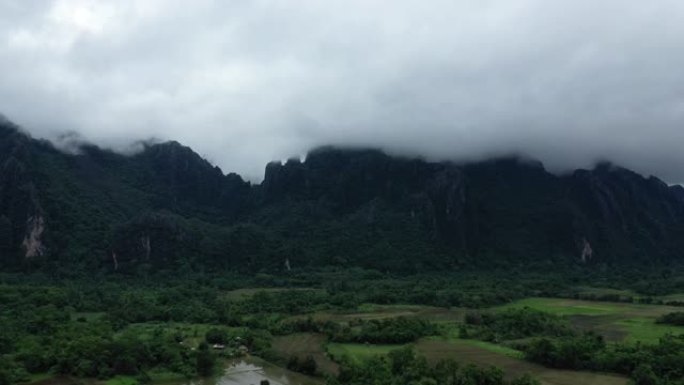 在雨中季风期间，老挝万旺的背景是稻田，森林和山脉的自然景观。