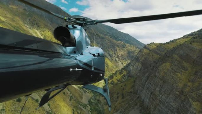 直升机飞过高山峡谷。从直升机尾部观看4k