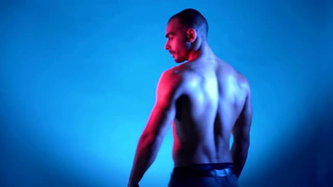 英俊强壮的运动男人在蓝色背景上展示和弯曲肌肉