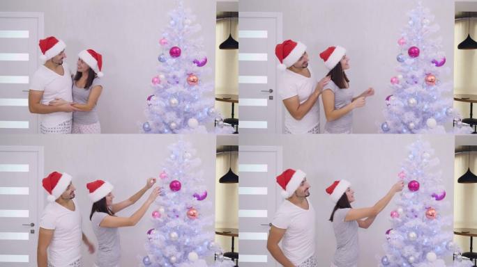 可爱的夫妇看着美丽的圣诞树，女人重新调整粉色玻璃球。