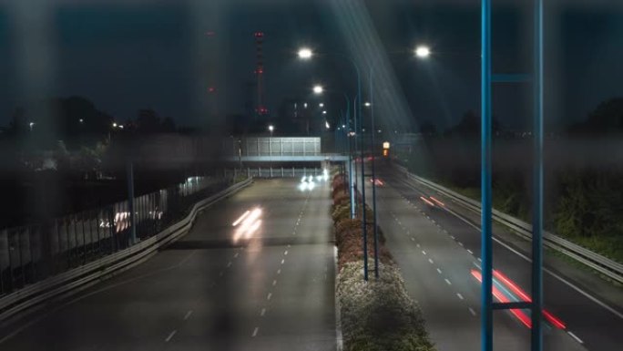 从道路安全铁丝网后面的立交桥拍摄的夜间高速公路的4k视频延时。