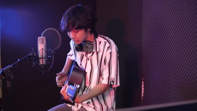 青年男歌手在录音室用吉他录制音乐，录音室概念