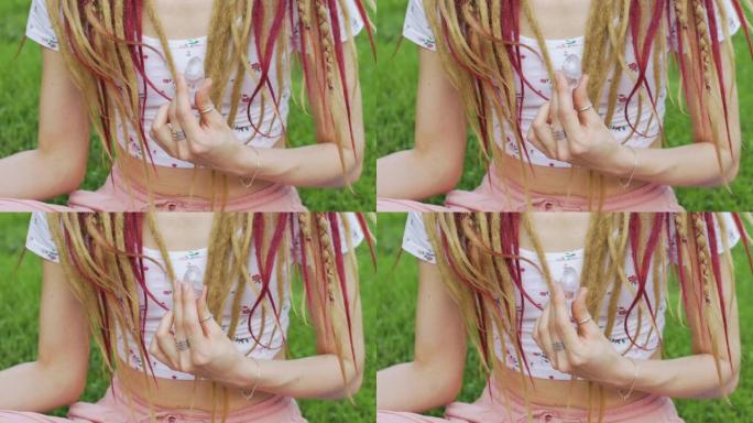 长辫子的成年女孩拿着透明的紫罗兰紫水晶约尼蛋，在户外的身体背景上进行虚拟健身、植入或冥想