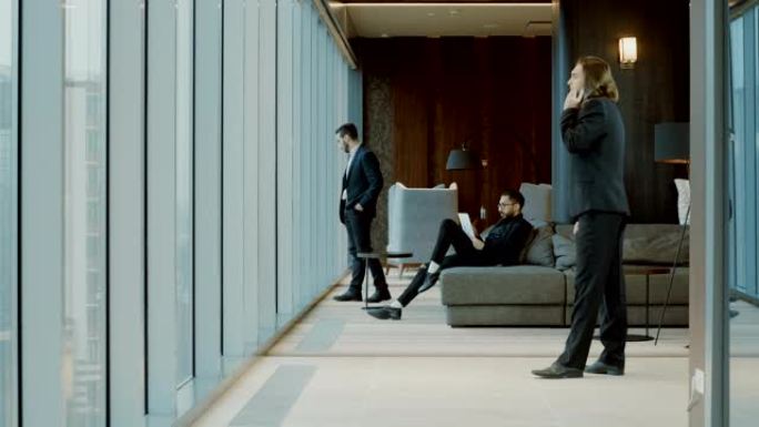 三个穿着黑色西装的男人在现代餐厅的全景窗户前。4K