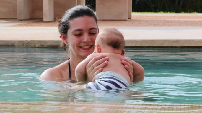 快乐的母亲与刚出生的婴儿儿子在游泳池水中