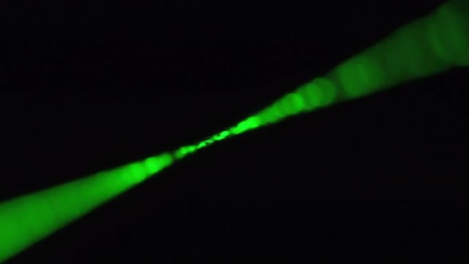 黑色背景上的绿色激光射线。功率激光束在雾中发光