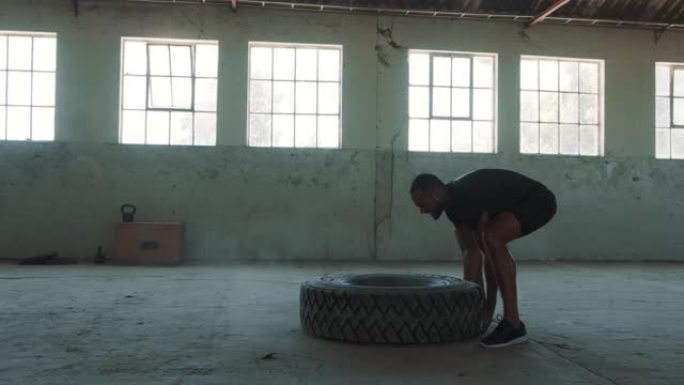 运动员在一个废弃的仓库里翻转轮胎