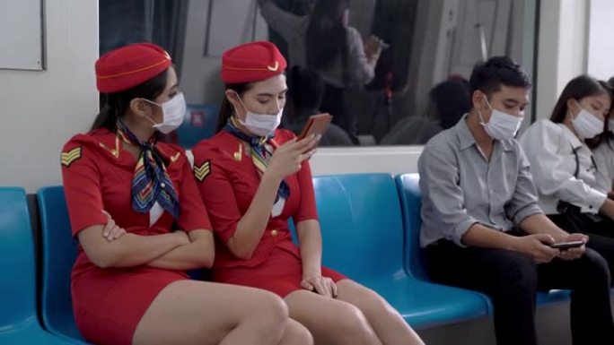 亚洲人使用带口罩的智能手机坐在地铁地铁上，女乘务员乘坐公共交通工具。大流行covid 19的概念新生