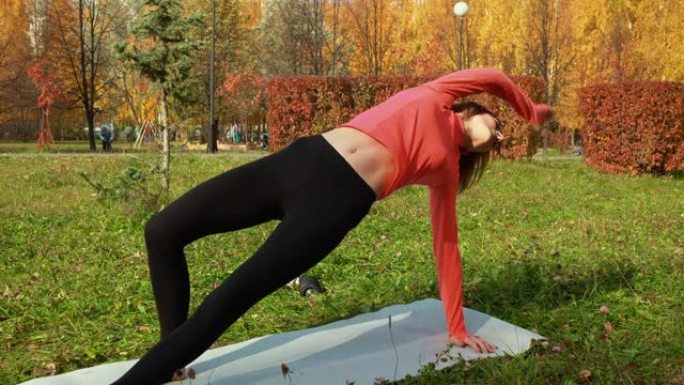 健身女子在城市秋季公园户外训练锻炼。运动教练在户外锻炼中练习伸展运动。练习体式的瑜伽女子。