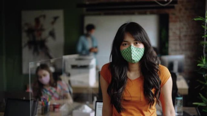 年轻的亚洲女商人自信地戴着口罩摆姿势