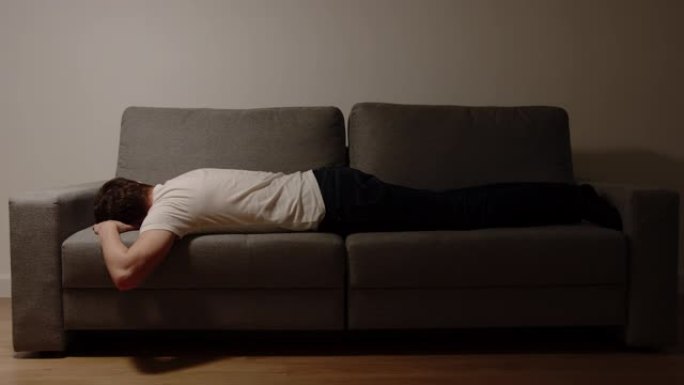 抑郁症: 年轻的成年男子晚上躺在沙发上