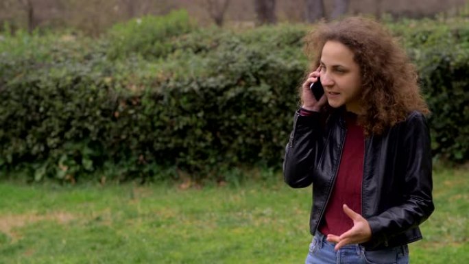 绝望的担心的年轻女子在公园里通过电话交谈。坏消息，担心
