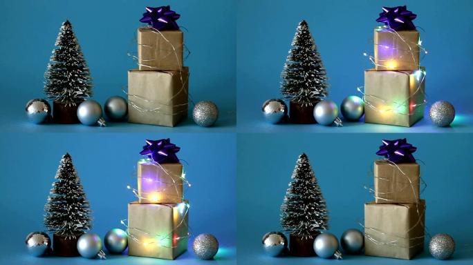 圣诞礼品盒包裹在闪烁的花环中，带有圣诞树和蓝色背景上的玩具。圣诞快乐!假日概念