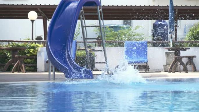 快乐的亚洲儿童玩水滑块，摔倒在游泳池上。