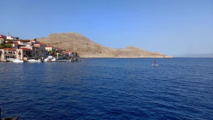 一名男子站在船上/航行，在希腊乡村丘陵的哈尔基岛 (Chalki) 兜售