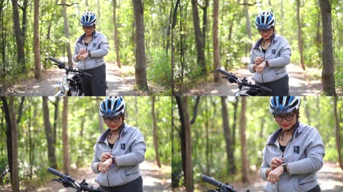 公园里的高级亚洲女性自行车，用智能手表检查时间或心率