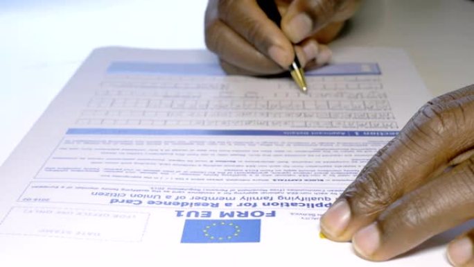 关闭非洲移民的手填写欧盟签证申请表。欧洲移民