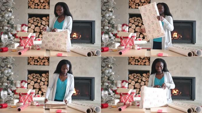美国黑人年轻女子独自在壁炉和圣诞树旁包裹圣诞礼物