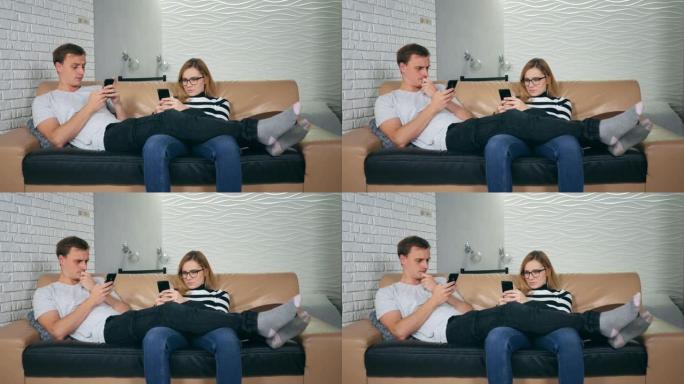 迷人的年轻夫妇坐在沙发上痴迷于智能手机。与手机相视对方为陌生人的夫妻，沟通问题和社交网络成瘾