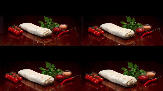 沙瓦玛 (Shawarma) 配以西红柿，辣椒和调味料，它们是其中的一部分，放在木制的涂漆桌子上。