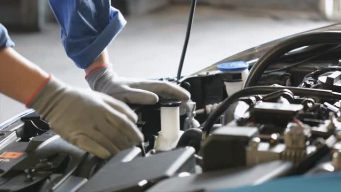 亚洲男子机械师检查闪耀火炬汽车发动机检查引擎中的错误。蓝色汽车用于汽车发动机的维修保险。用于运输汽车
