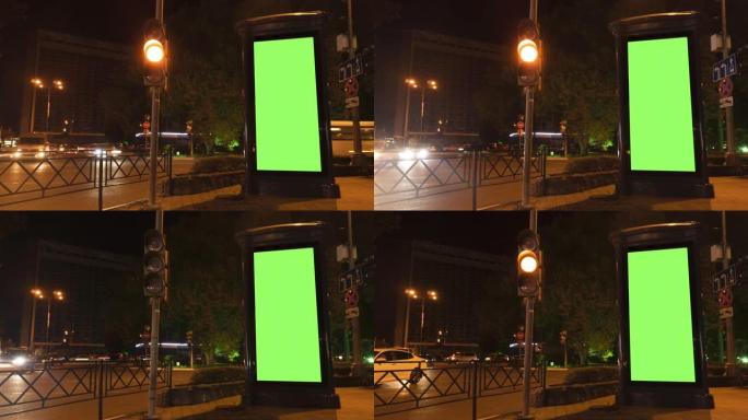 在时间流逝的繁忙夜晚街道上带有空绿色屏幕的特写广告牌