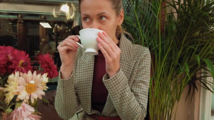 一名年轻女子在巴黎的一家复古餐厅喝咖啡。复古风格的咖啡馆，配有充满活力的花朵和复古家具