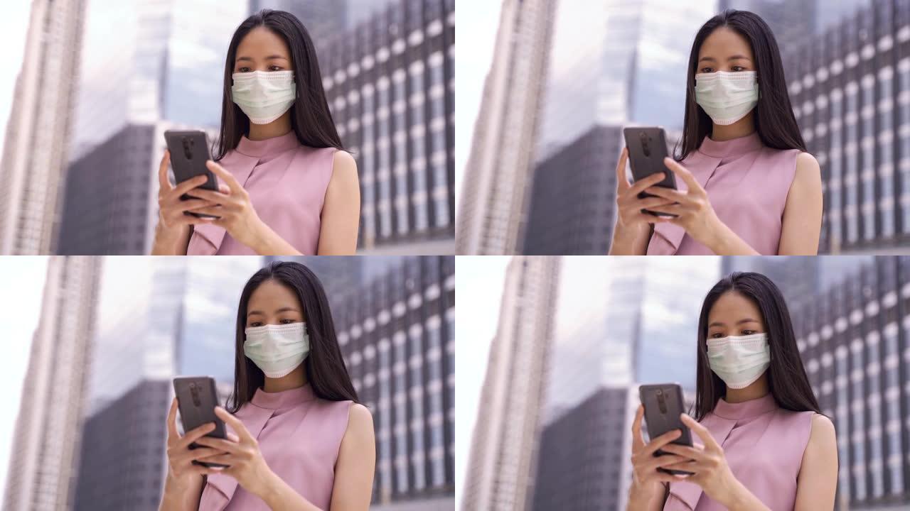 亚洲女商人戴着防护冠状病毒脸掩盖手机短信在城市环境，集中，城市生活，流行病，工作生活