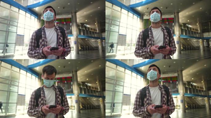 延迟。新常态。在航站楼机场戴口罩阅读信息的男子。旅行者使用智能手机在机场航班时刻表附近在线办理登机手