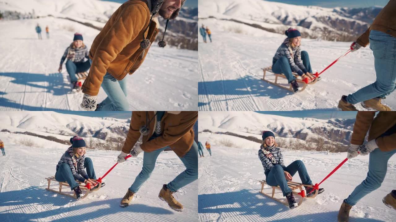 年轻的家伙把他的女朋友拉到山上的雪橇上，而她却在享受和大笑