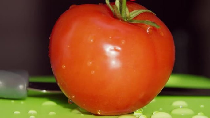 红色成熟的西红柿用大厨刀在木板上切成，宏观，水滴