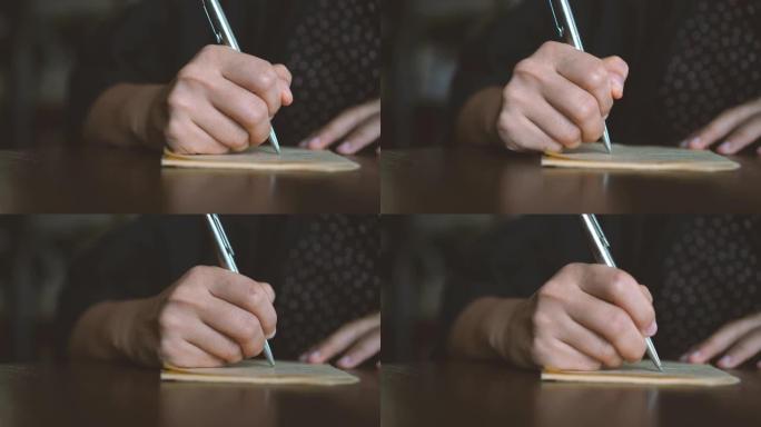 4k视频复制空间的人用手在白色笔记本上写下来，用计算器在咖啡馆背景下用bokeh灯计算。