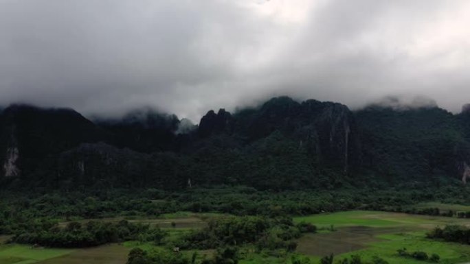 在雨中季风期间，老挝万旺的背景是稻田，森林和山脉的自然景观。