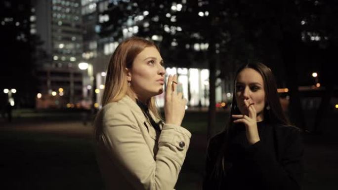 两个漂亮的年轻女子抽烟，将烟雾吸入肺部