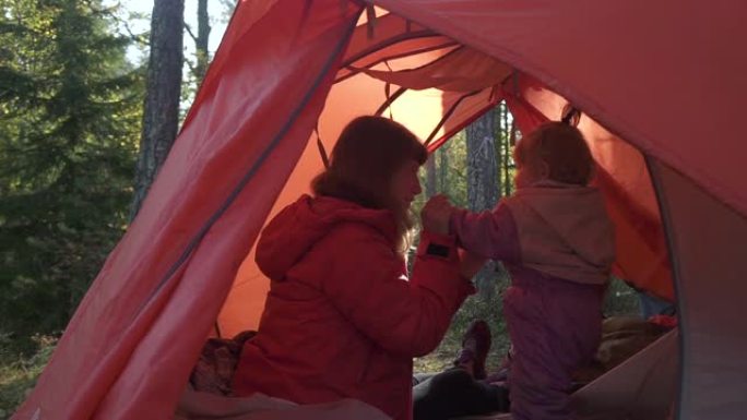 妈妈和小女儿在红色帐篷露营大自然里玩耍