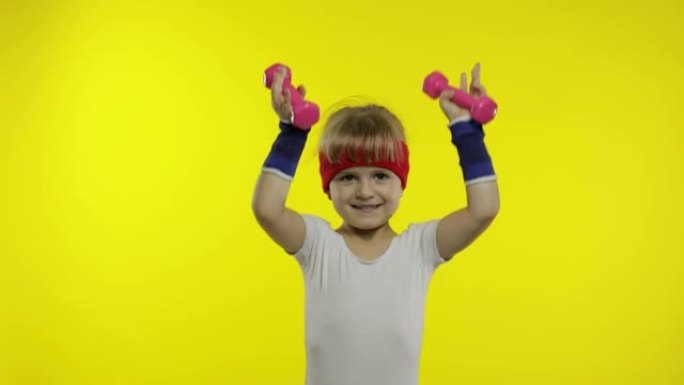 穿着运动服的高加索女孩用哑铃做练习。孩子们的锻炼。运动儿童