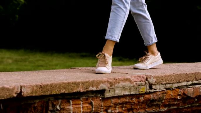 现代舞者的脚穿着运动鞋在砖墙上跳舞的特写镜头。4K