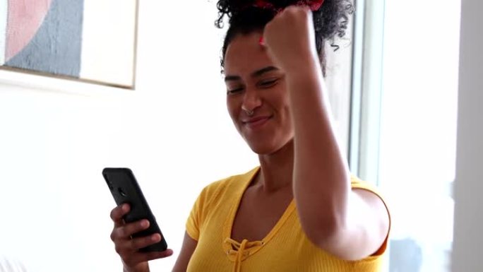 骄傲的年轻黑人妇女庆祝手持手机的成功