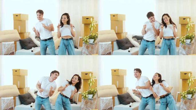 年轻夫妇搬进新公寓。男人和女人站在一起跳舞。朝同一方向移动他们的身体。在新公寓玩得开心。