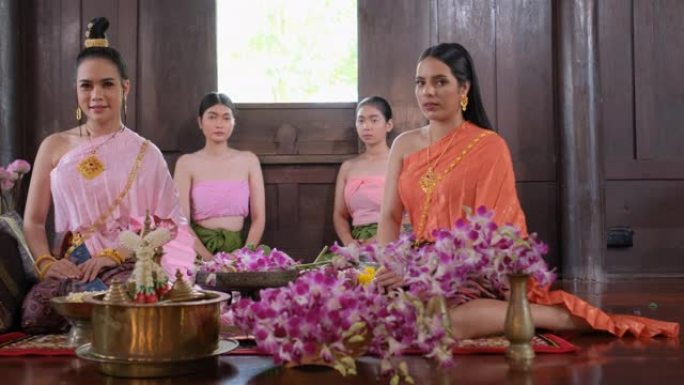 一群穿着泰国传统服装的花工作的泰国妇女住在古房子里，然后对相机表示敬意
