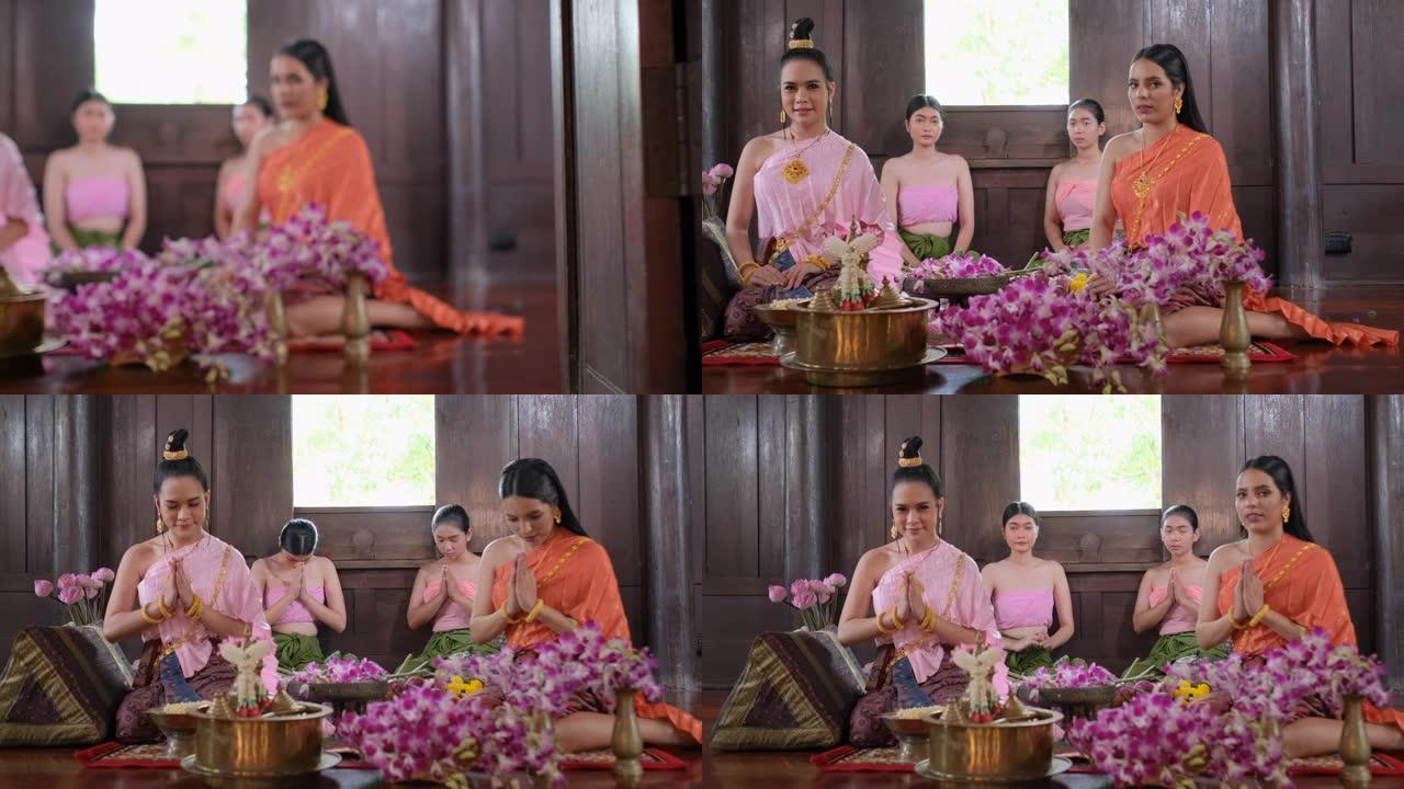 一群穿着泰国传统服装的花工作的泰国妇女住在古房子里，然后对相机表示敬意