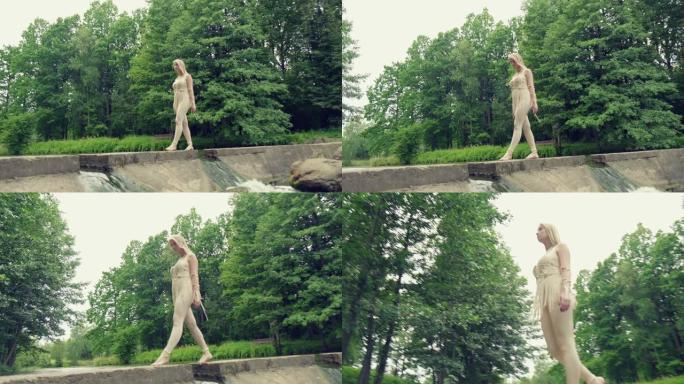 一个金发女孩走过水流的桥。自然美。