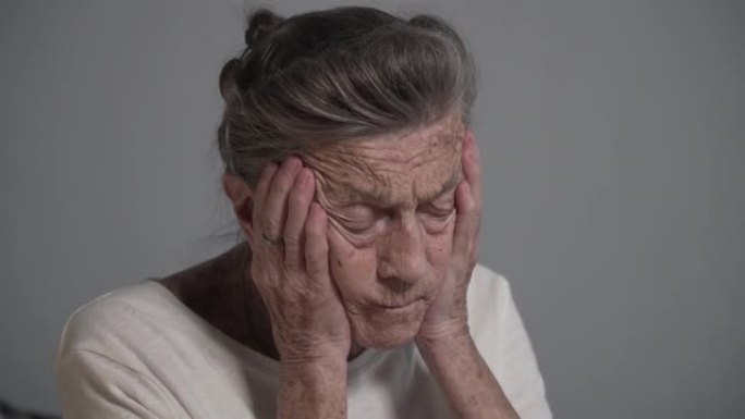 在家头痛的高级女性。带着皱纹和白发的老奶奶抱着头高血压和偏头痛寻求帮助。医疗保健概念。有痛苦的感觉偏